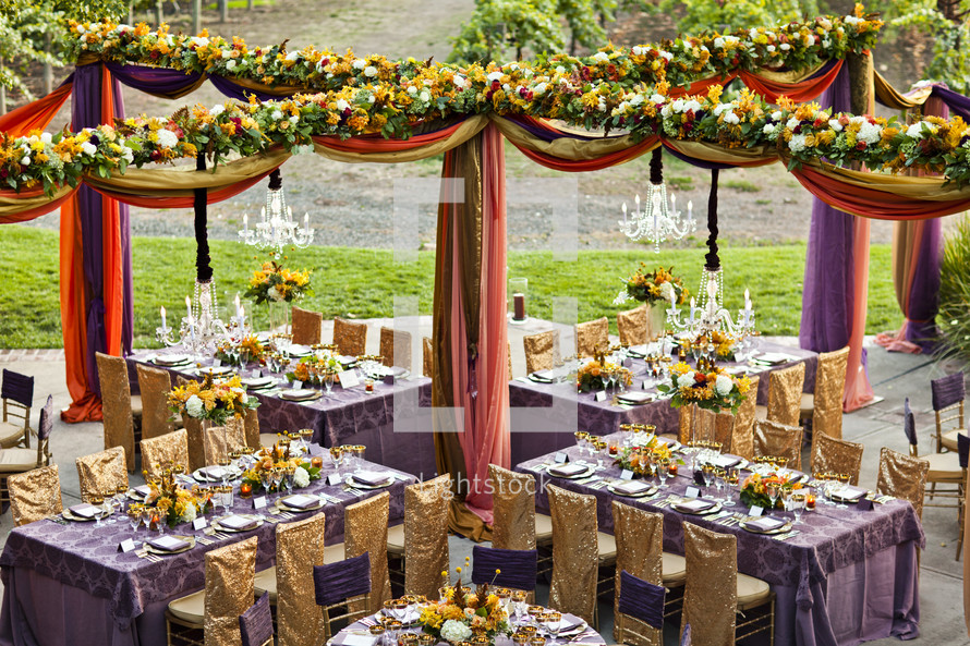 ornately decorated tables at a wedding reception, gold, purple wedding design , floral drapes chairs linens dinner