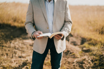 a man standing outdoors holding a Bible 