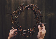 hands of Christ holding up a crown of thorn 