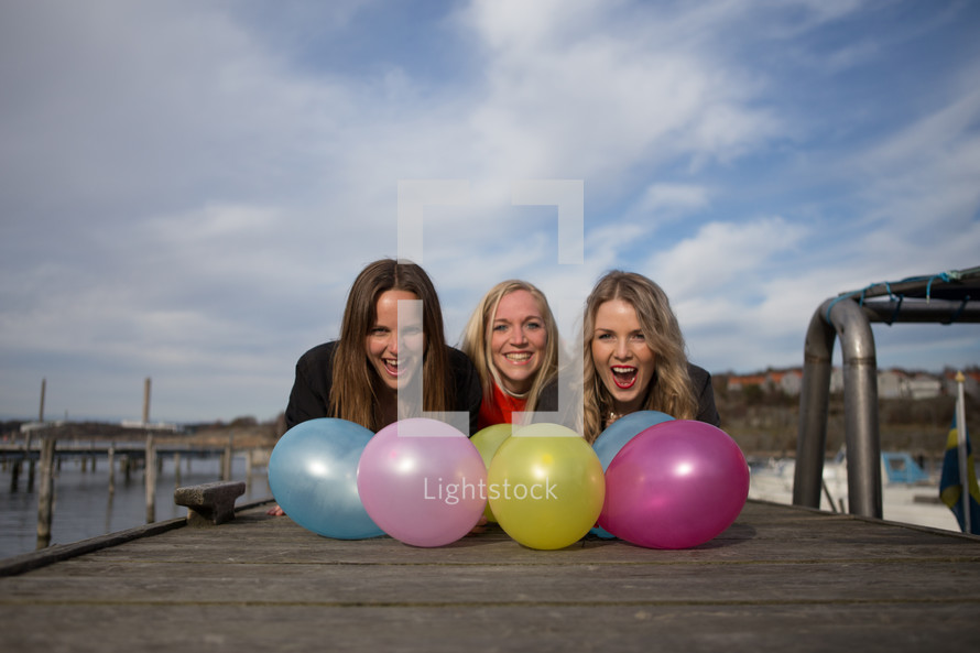 women with balloons on a dock 