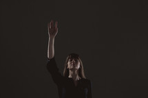 A woman standing with raised arm in praised to God 