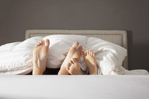 Parent's and Child's feet sticking out from the blanket at the end of the bed.
