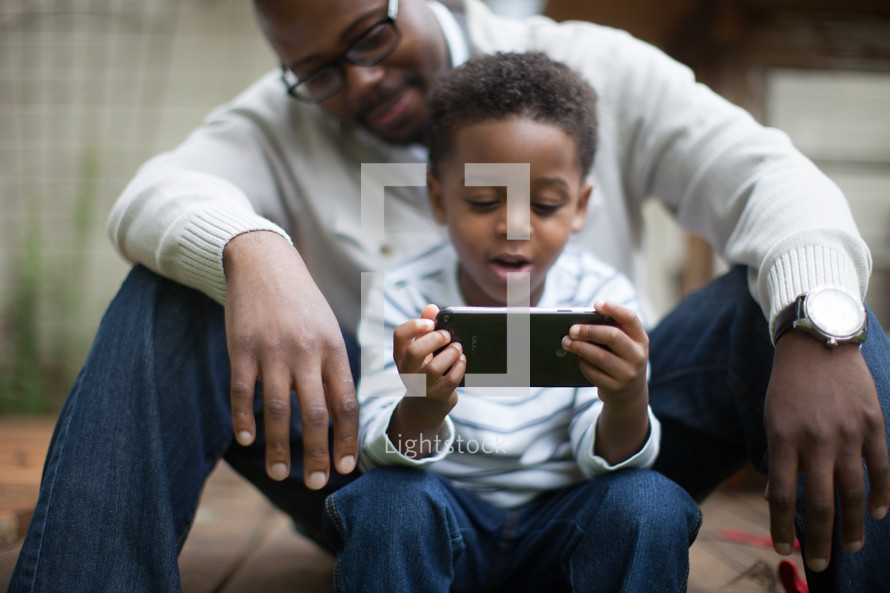 father and son looking at a cellphone screen 