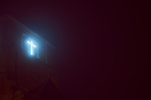 glowing cross light from a church on a foggy night 