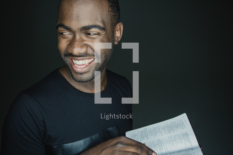 man smiling holding an open Bible 