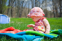 a baby sitting on a blanket in the grass