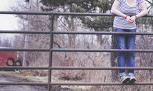 young woman standing on a metal gate 