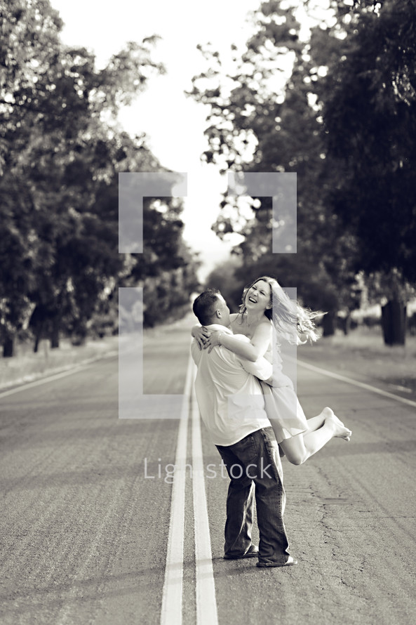 Happy couple outdoors man twirling girl spinning standing in road joy engagement