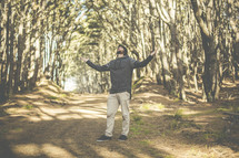 a man with outstretched arms praising God in a forest 