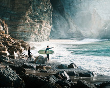 surfers on a rocky beach 