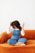 Woman shaking her hair back and forth on an orange couch 