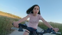 POV of a young girl enjoying a bicycle ride on the rural countryside.