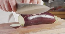 Slow motion close up of a chef knife slicing an Eggplant