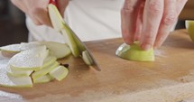 Close up of a chef knife slicing a green apple