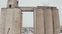 Drone shot of grain elevator in a small rural town on a snowy winter day.