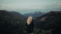 a woman standing on a mountaintop taking in the view 