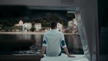 a man sitting on a boat looking out at the water 