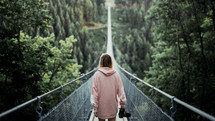 a woman with a camera crossing a swinging bridge 