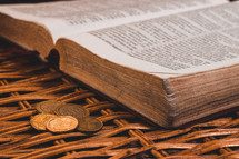 open Bible and coins in a basket 