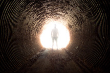 a man standing in a tunnel of glowing light 