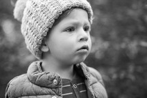 face of a toddler boy in a wool cap and vest 