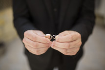 groom in a tuxedo holding wedding rings 