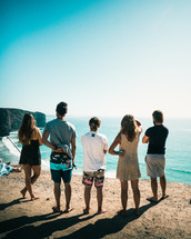 friends standing on cliffs overlooking a beach 