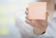 a woman holding a pad of blank sticky notes 