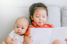 big sister reading to her infant brother 