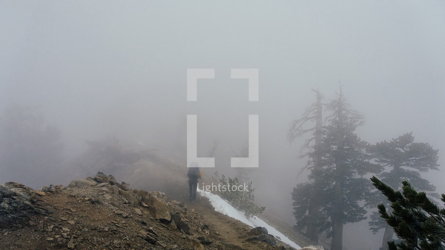 person hiking on foggy mountainside 
