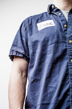 Man in a denim shirt with a visitor's tag on.