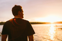 man standing at a shore at sunset 