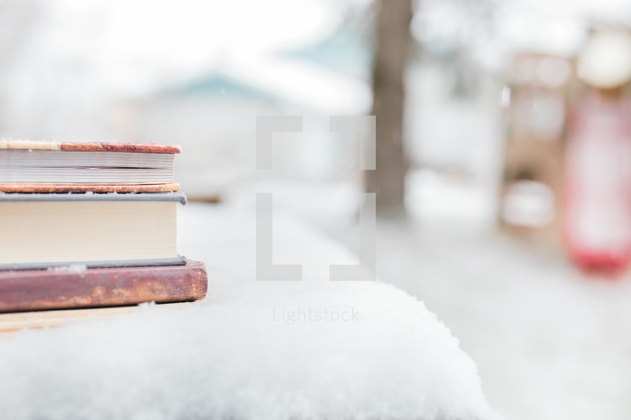 a stack of books on a table in the snow 