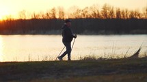 Nordic walking. Silhouette of an elderly man with Nordic walking sticks at sunset.