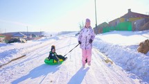 Funny children sliding on snow tubing on slope outdoors in winter. Kids sledding slide down hill. Winter fun activity outdoor.