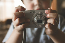 Child holding a digital camera.