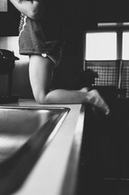 Child kneeling on top of a kitchen counter.