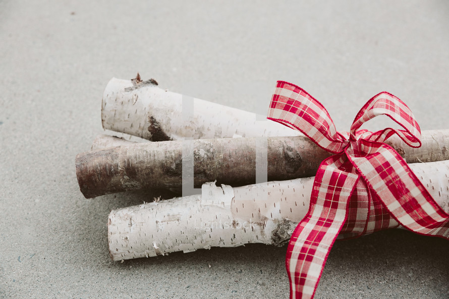 Birch logs tied with a red and white ribbon.