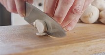 Close up of a chef knife slicing champignon mushrooms