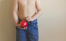 torso of a boy child holding a red apple 