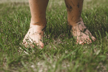 A toddler barefoot in the grass.