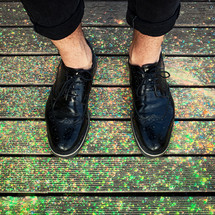 Close up of feet with polished shoes on colored powder