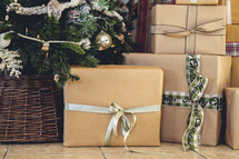 Stacked brown paper wrapped gifts near tree
