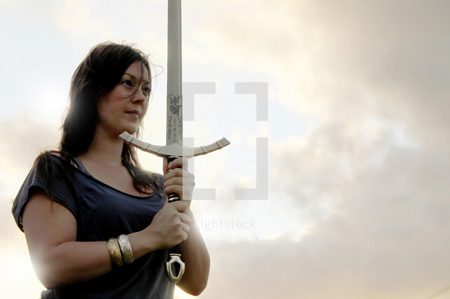 Warrior woman with a focused gaze as she holds up her sword. 