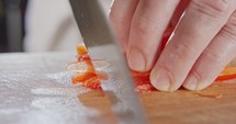 Extreme macro of a chef knife slicing a red bell pepper