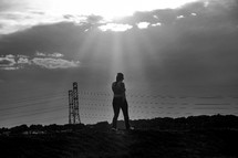 a woman walking towards power lines at sunset 