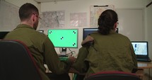 Israeli soldiers in a military command and control room looking at screens