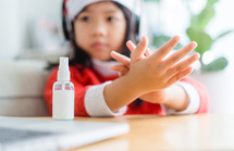 a child using hand sanitizer dressed in a Santa Suit 