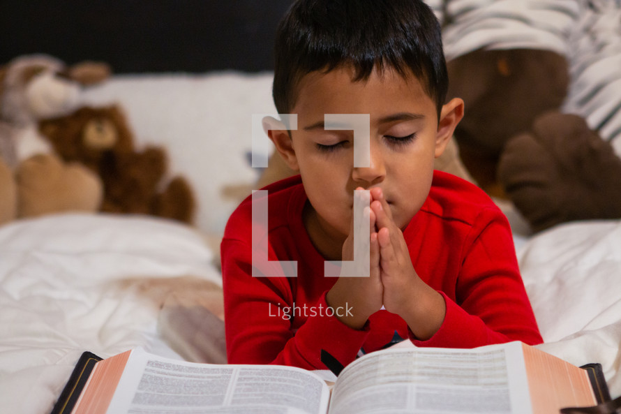 child reading a Bible in bed