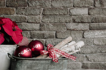 An arrangement of Christmas decorations against a backdrop of a gray brick wall.